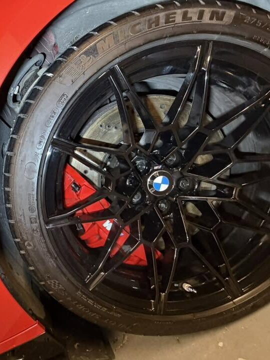 Gloss black BMW M wheel and red brake caliper cleaned by ASR Detailing